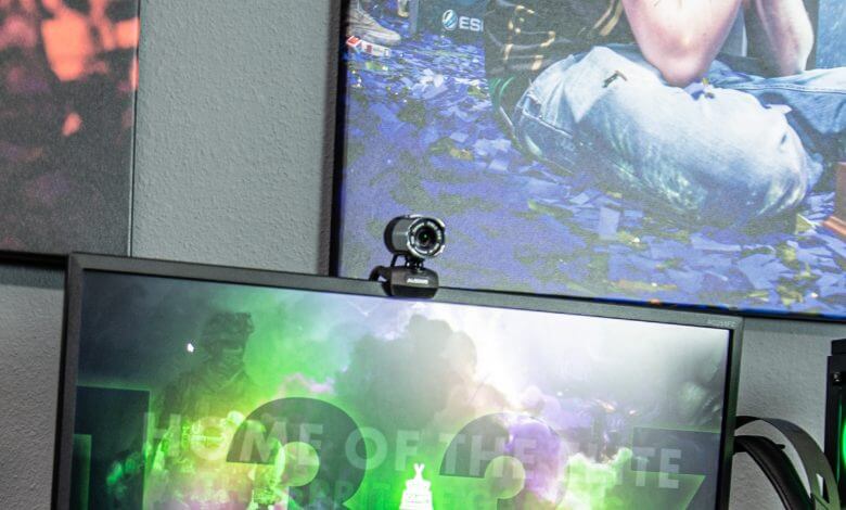 Uma imagem de setup de gamer livestreamin com um monitor e uma webcam acima dele
